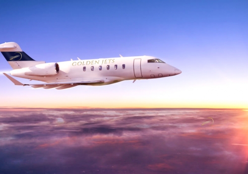 Private jet plane flying above clouds in sunset